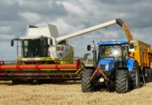 blue tractor next to white farm vehicle at daytime