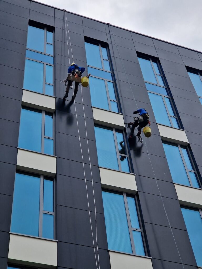 low angle shot of people cleaning the windows in a modern building in city