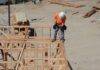 man standing with drill on house construction