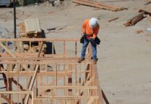 man standing with drill on house construction