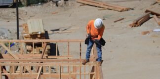 man standing with drill on house construction