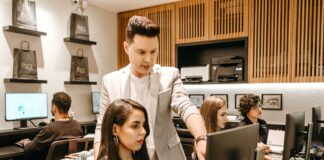 man teaching woman in front of monitor
