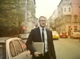 determined smiling businessman with laptop on street
