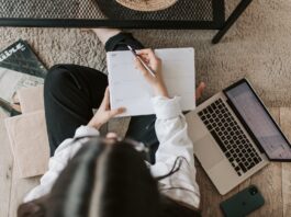 faceless lady with notebook and laptop on floor at home