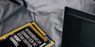 modern laptop and books near smartphone on crumpled bed