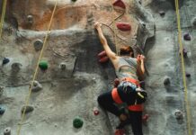 unrecognizable climber ascending artificial rock during practice