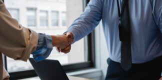 crop colleagues shaking hands in office