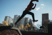 fit man jumping from brick parapet in urban city