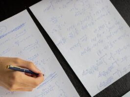student writing in papers with homework task