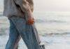 anonymous barefooted woman strolling on wet sandy seashore