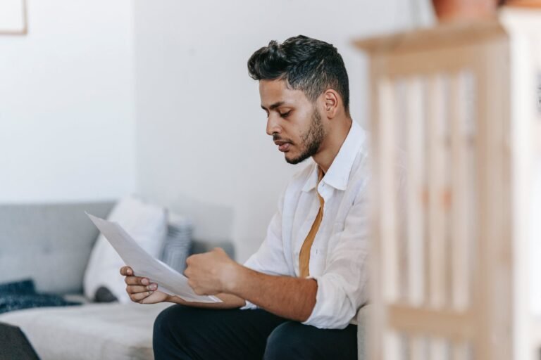 thoughtful ethnic man reading documents on sofa