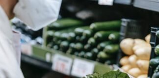 unrecognizable customer in medical mask with lettuce in supermarket