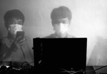 male worker using laptop and phone during coronavirus pandemic