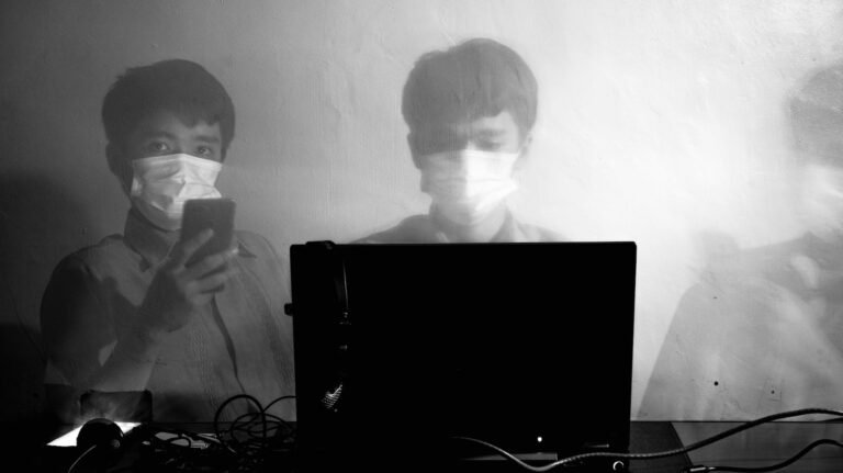 male worker using laptop and phone during coronavirus pandemic