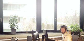 man with headphones facing computer monitor