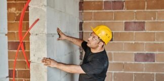 man in black t shirt and blue denim jeans holding a concrete wall