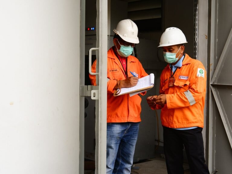 men in orange jacket and hardhat standing on the doorway