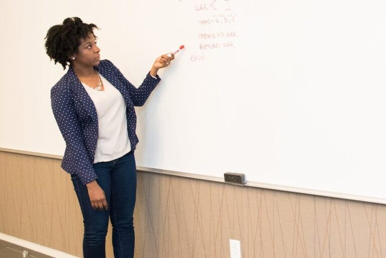 woman wearing black blazer holding pen pointing white marker board