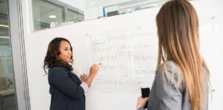 woman in black blazer looking at woman in grey blazer