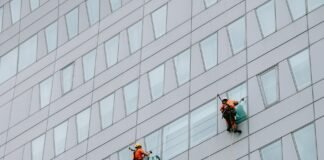 two male rope access workers washing the windows of a modern building