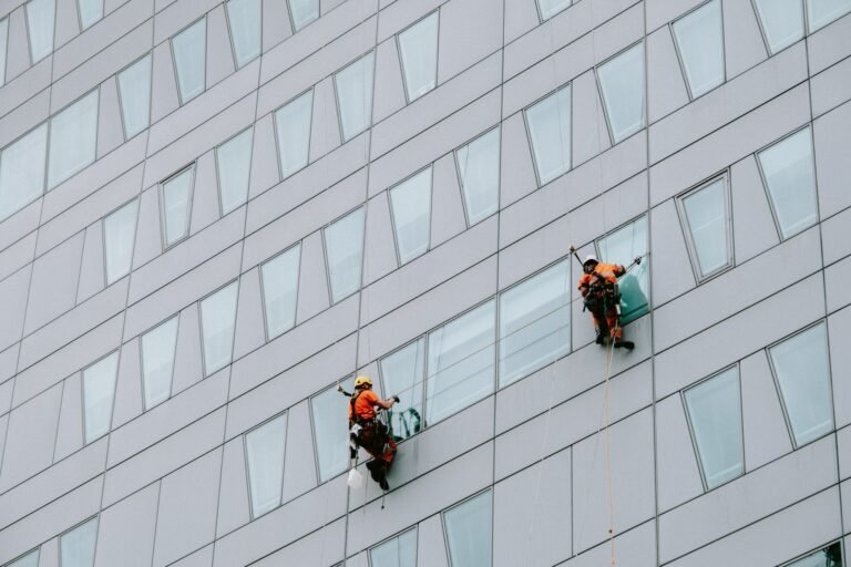 two male rope access workers washing the windows of a modern building
