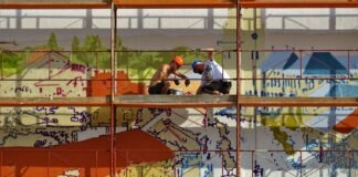 two person on scaffolding painting wall