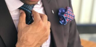 man in formal suit jacket holding his necktie