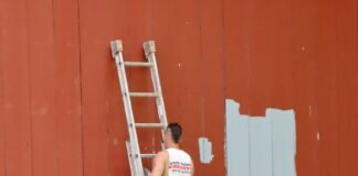 two men in white work uniforms using ladder to repaint a wooden wall