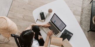 young lady typing on keyboard of laptop in living room