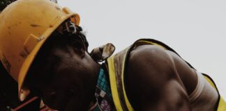 focused black man hammering nail working in construction site
