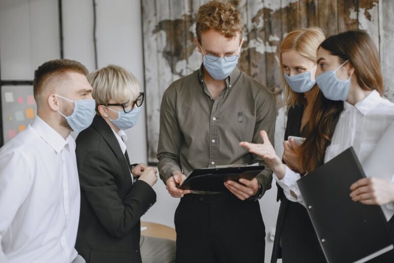 group of people talking in office wearing masks
