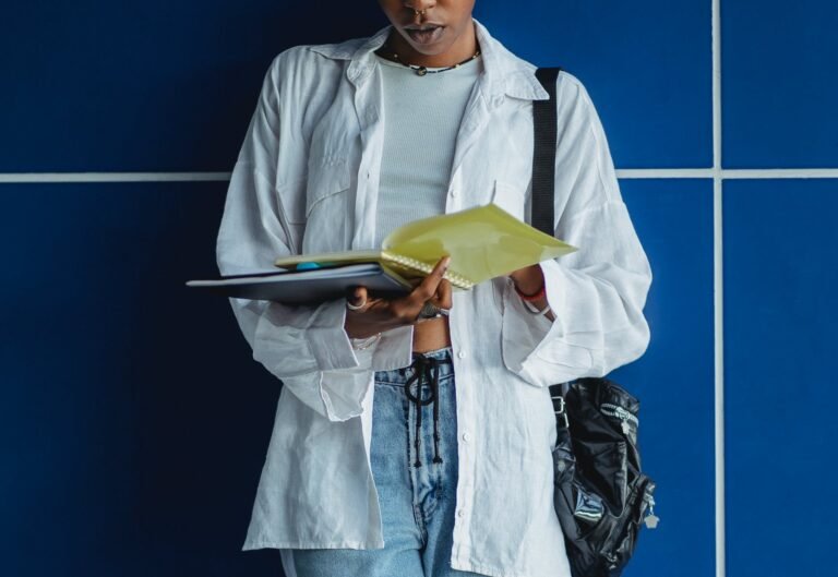 crop black female student reading copybook near wall