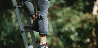 faceless camper climbing ladder in forest