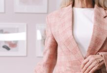 woman in pink and white plaid blazer sitting on brown wooden chair