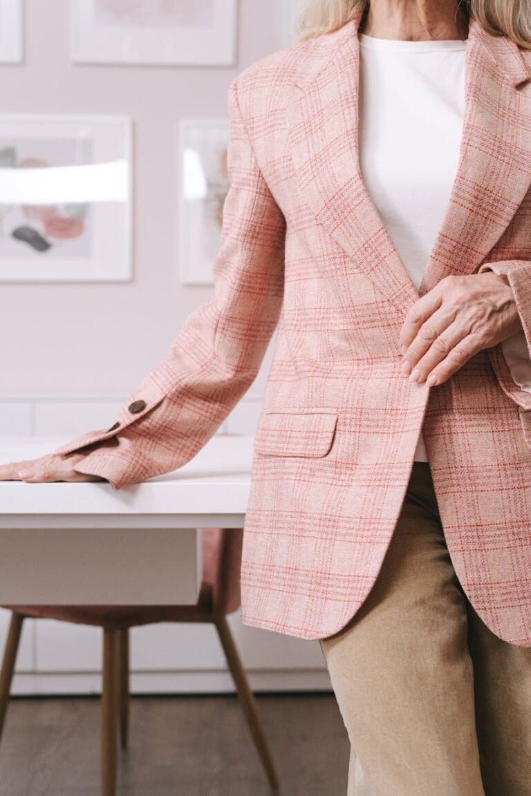 woman in pink and white plaid blazer sitting on brown wooden chair