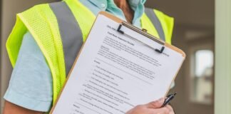 person in yellow reflective safety vest holding a pen and checklist of house inspection