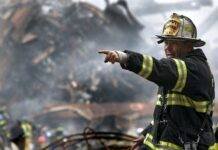 fire fighter wearing black and yellow uniform pointing for something