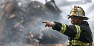 fire fighter wearing black and yellow uniform pointing for something