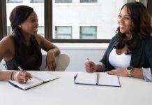 two woman in black sits on chair near table