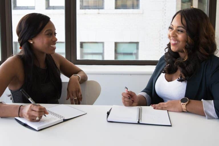 two woman in black sits on chair near table