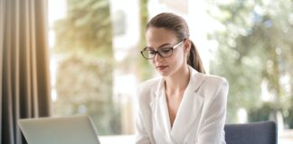 concentrated female entrepreneur typing on laptop in workplace