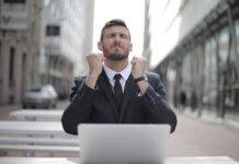 man in black suit sitting on chair beside buildings