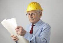 senior male engineer reading blueprint in studio
