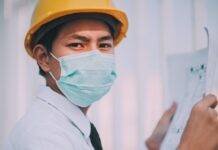 man wearing a mask holding a blueprint
