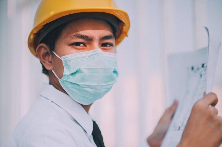 man wearing a mask holding a blueprint