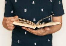 faceless man in tee shirt paging interesting book