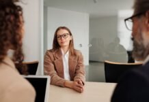 woman in brown blazer seated beside table