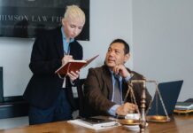 diverse serious law office colleagues taking notes and using laptop