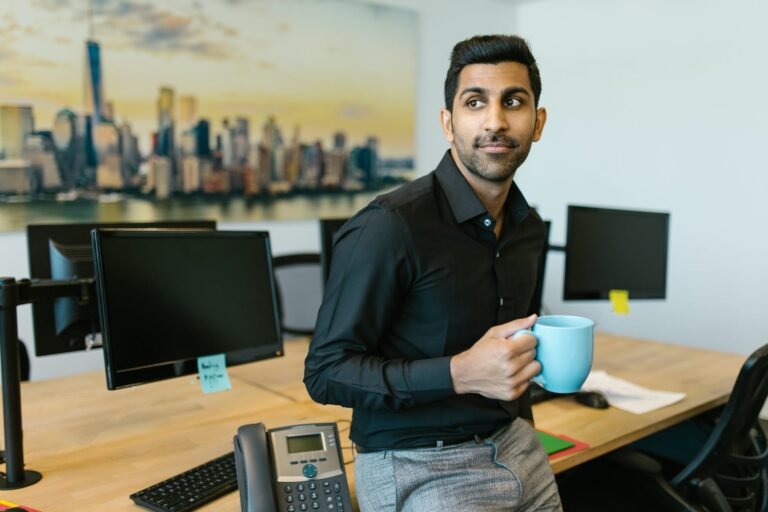 man in black dress shirt leaning on a desk