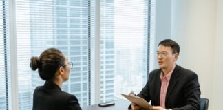man in glasses holding a folder while talking to a woman in suit